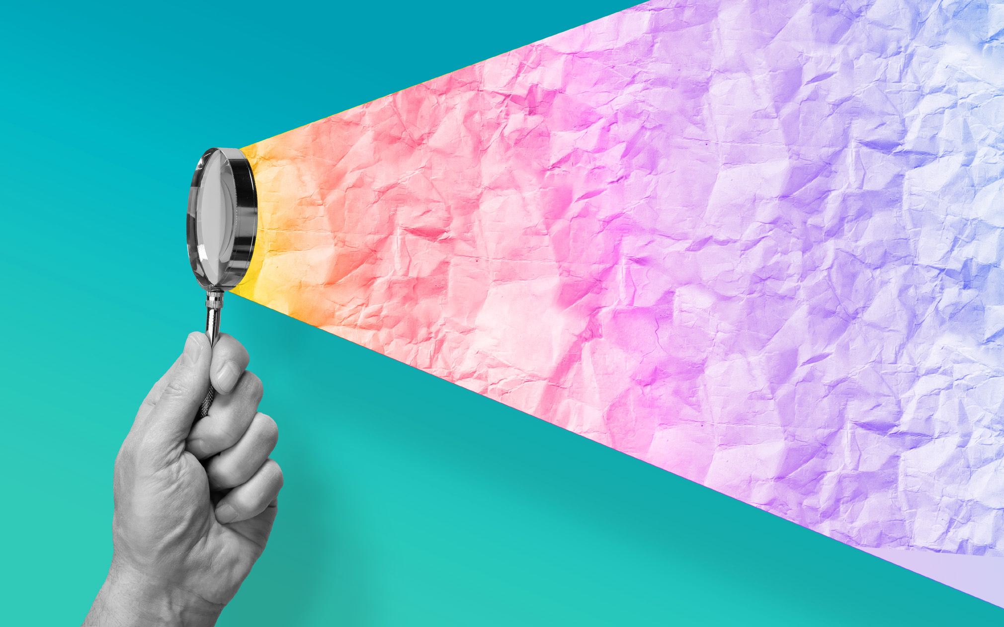 Hand holding a magnifying glass over a teal background and a multicolored projection